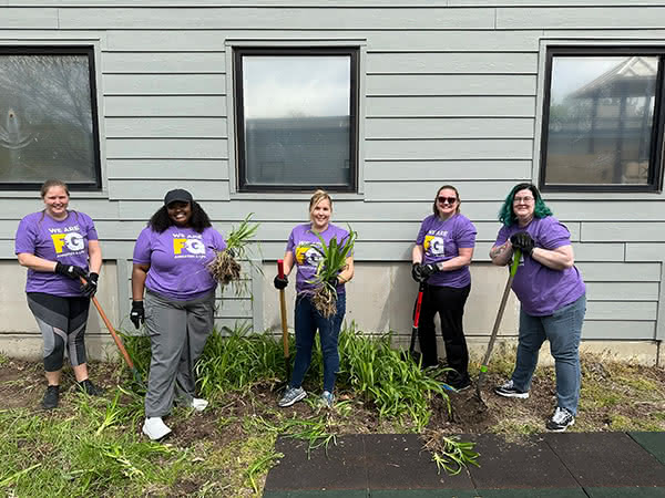F&G Employees cleaning up weeds outside a community center