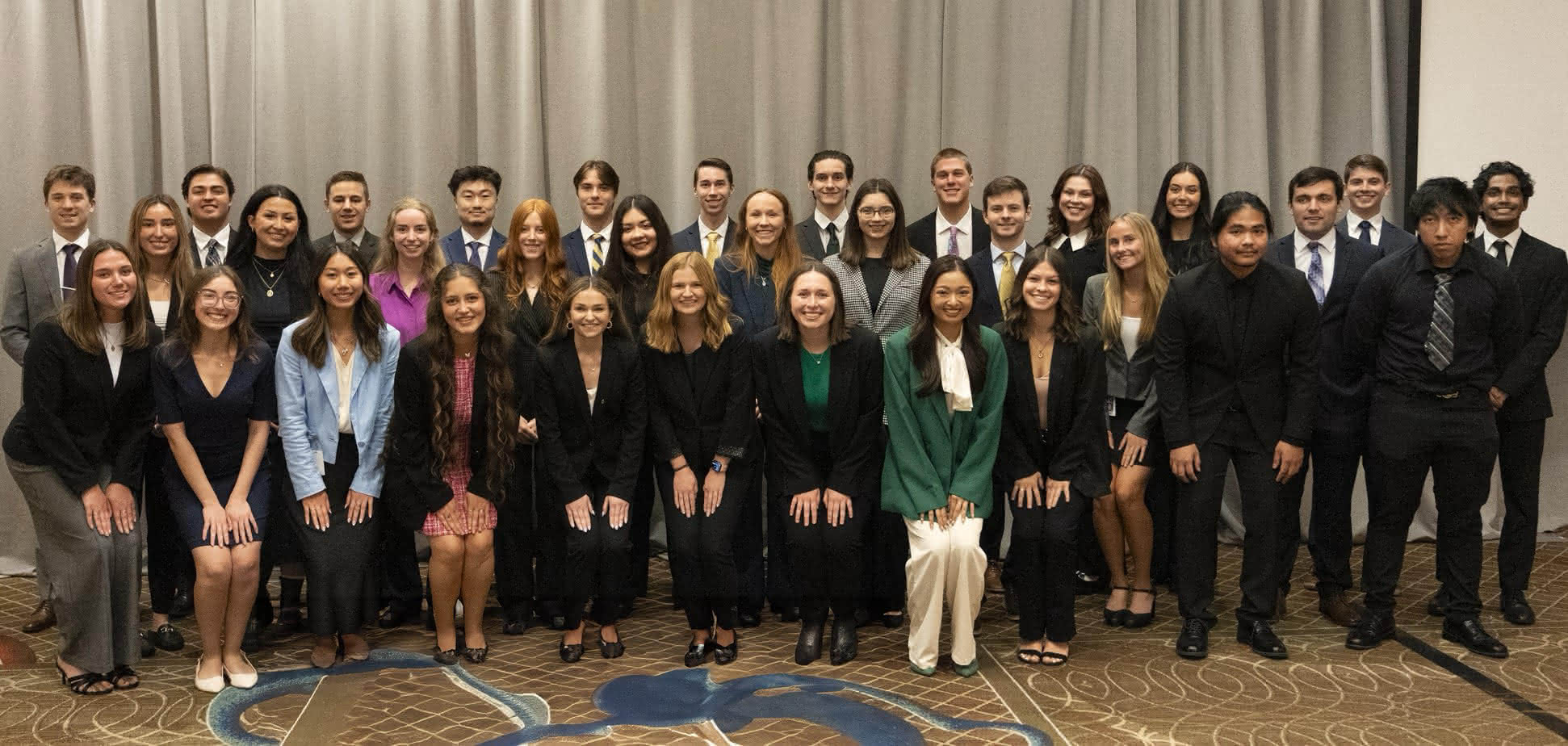 The full intern cohort standing together dressed in business attire