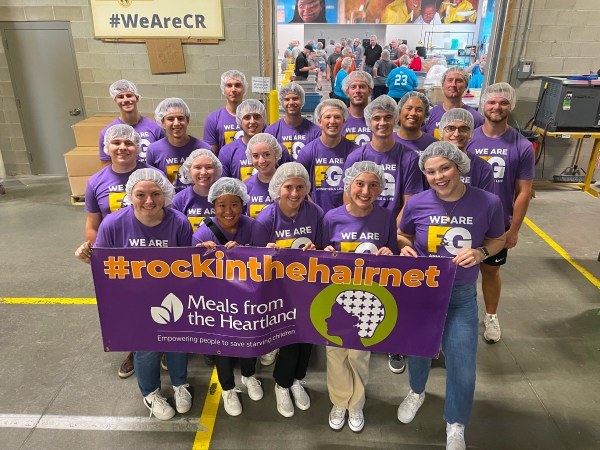 Interns wearing F&G branded purple shirts and holding a banner that says #rockinthehairnet