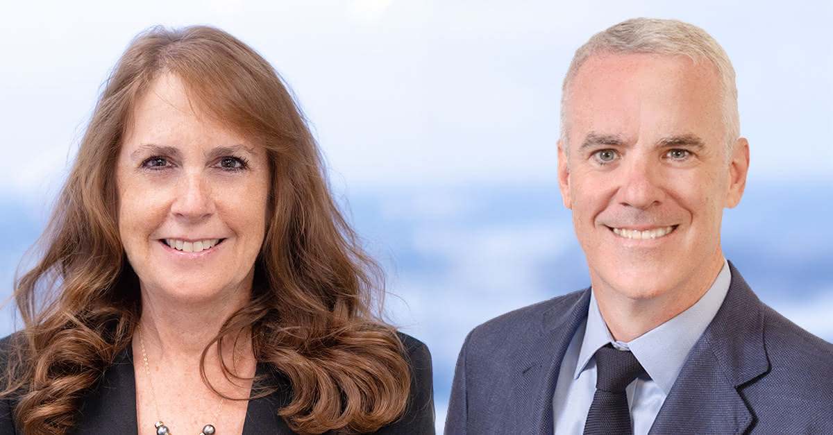 Conor and Wendy in front of window together with a blurred cityscape behind them