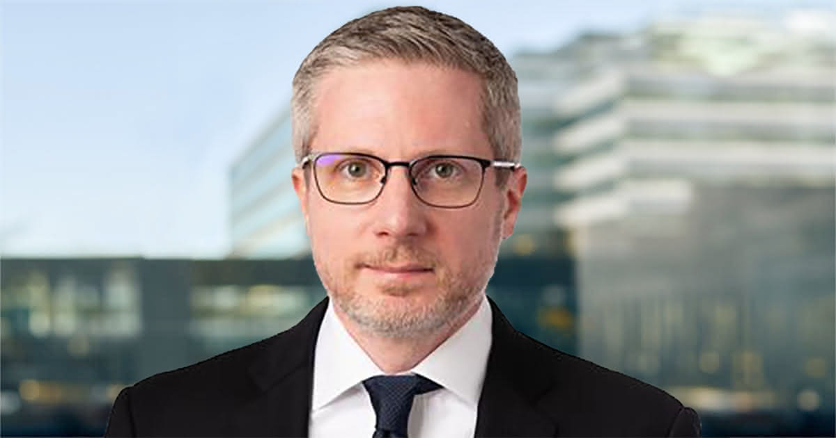 Donny Leintz smiling in front of a window showing the skyline of Des Moines Iowa